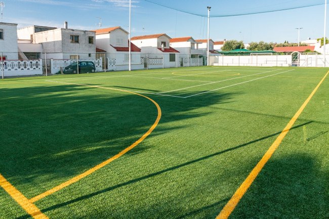 Campo da calcio con erba sintetica e case vicine.