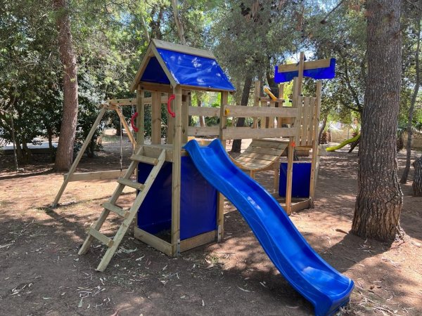 Area giochi con scivolo blu e struttura di legno.