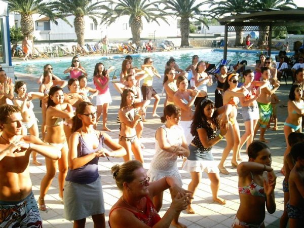 Persone che ballano in gruppo a bordo piscina.