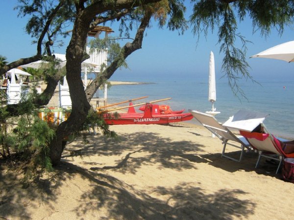 Barca di salvataggio rossa su spiaggia sabbiosa.