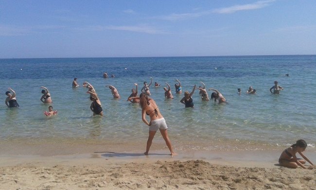 Persone che fanno esercizi in acqua in spiaggia.