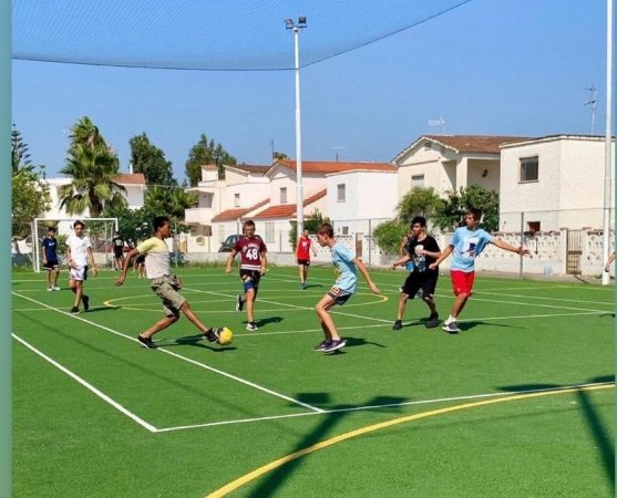Giovani che giocano a calcio su un campo all'aperto.