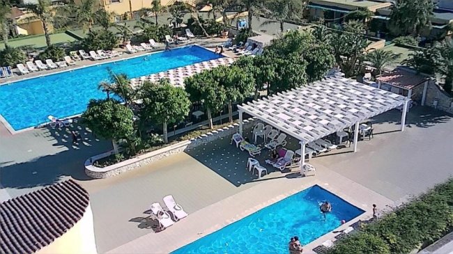 Vista dall'alto di due piscine con lettini e gazebo.