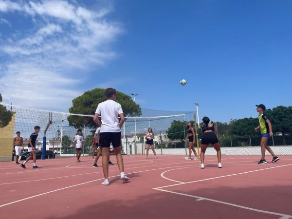 Partita di pallavolo all'aperto su campo rosso.