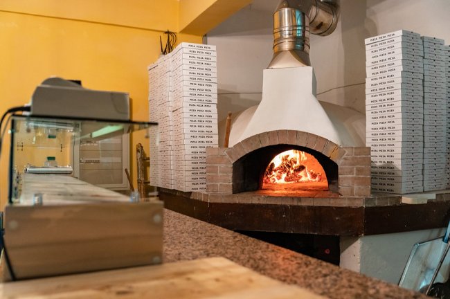 Forno a legna per pizza con scatole accatastate.