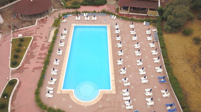 Piscina rettangolare vista dall'alto con sdraio bianche.