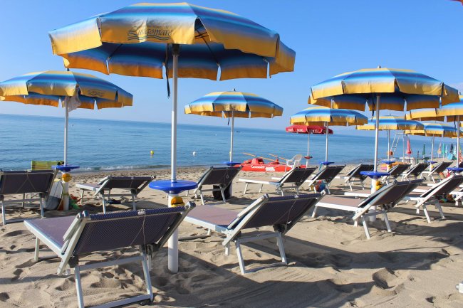 Spiaggia con ombrelloni gialloblù e lettini.