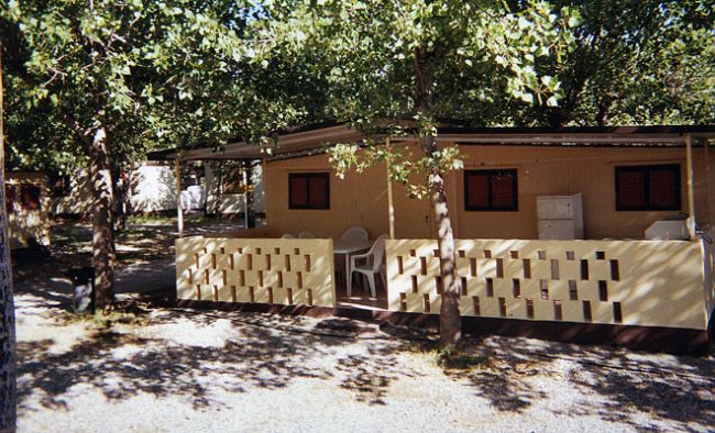 Una struttura in muratura gialla con terrazza recintata, circondata da alberi.