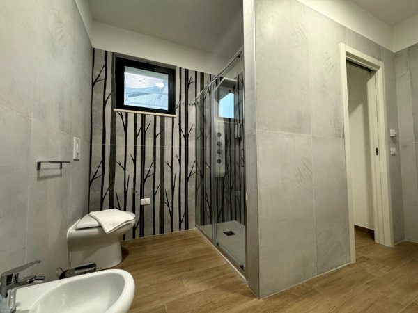 Bagno con doccia e piastrelle grigie.