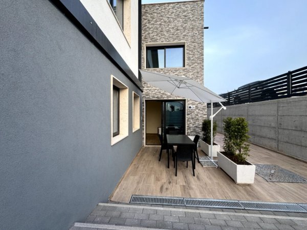 Esterno moderno con patio e ombrellone.