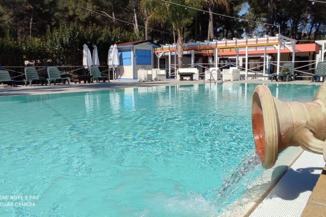 Piscina all'aperto con archi d'acqua e sdraio.