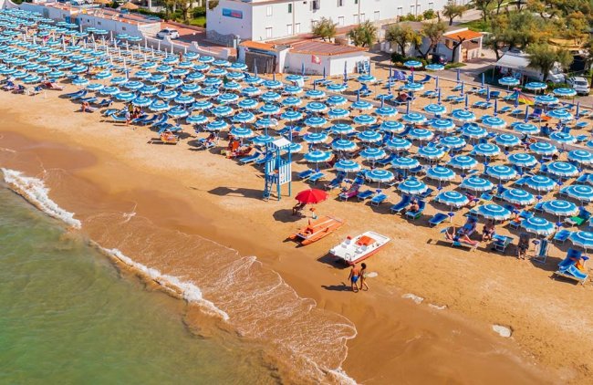 Spiaggia con file di ombrelloni blu.