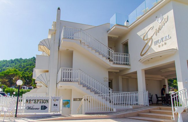 Ingresso di un hotel bianco con scale esterne.