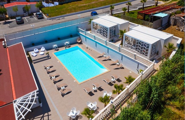 Piscina circondata da lettini e cabine moderne.