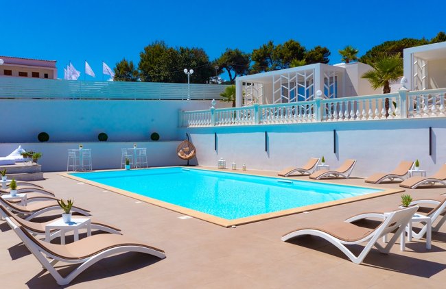Piscina circondata da sdraio e cabine bianche.