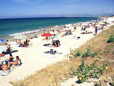 Una spiaggia affollata con ombrelloni colorati e persone che prendono il sole vicino all'acqua.