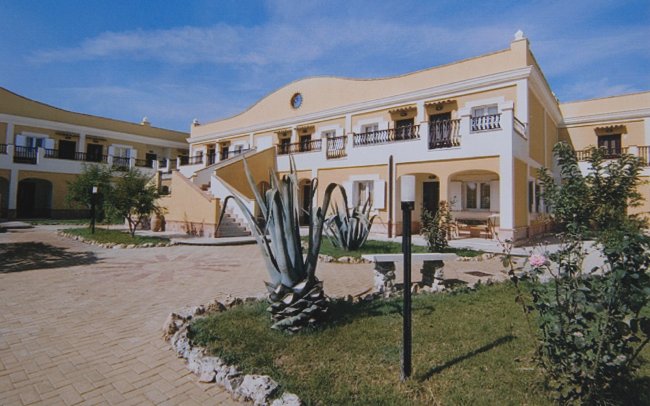 Edificio a due piani circondato da piante.