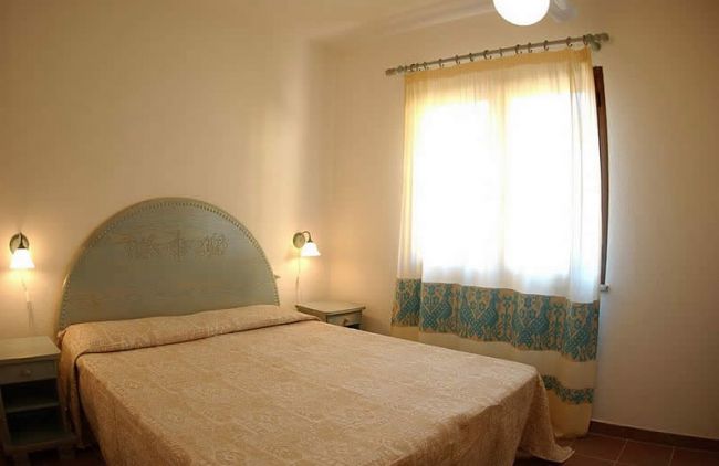 Camera da letto con letto matrimoniale e finestre luminose.