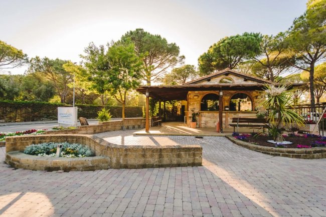Edificio di pietra in un giardino con vialetti lastricati e piante rigogliose.