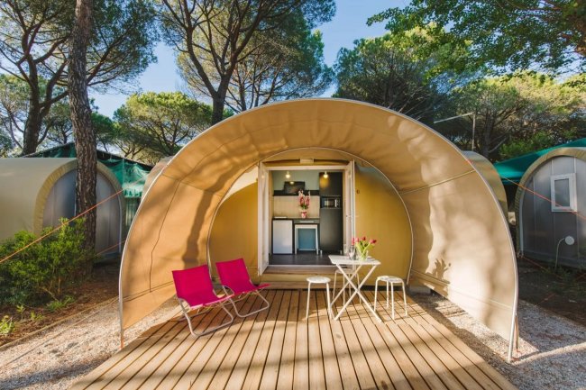 Tenda a cupola con sedie e tavolino su una pedana in legno.