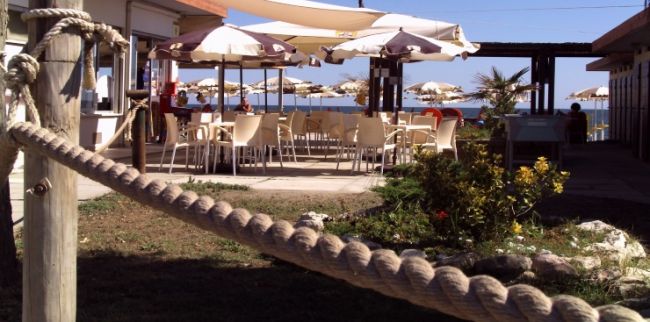 Tavoli con ombrelloni all'aperto vicino al mare.