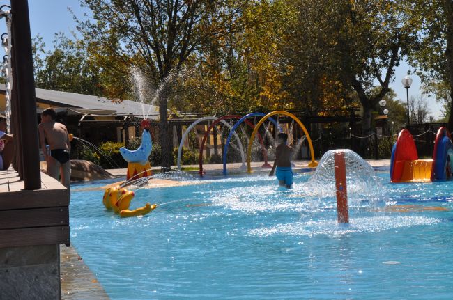 Bambini giocano in una piscina con giochi d'acqua colorati.