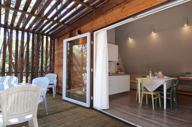 Veranda in legno con tavolo e sedie bianche.
