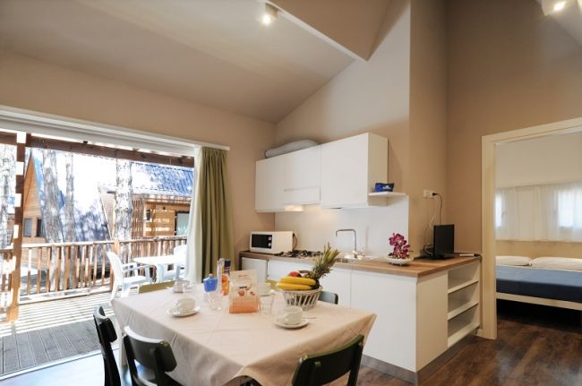 Cucina moderna con tavolo apparecchiato e vista su veranda.