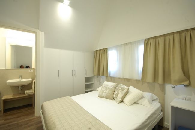 Camera da letto luminosa con letto matrimoniale e bagno annesso.