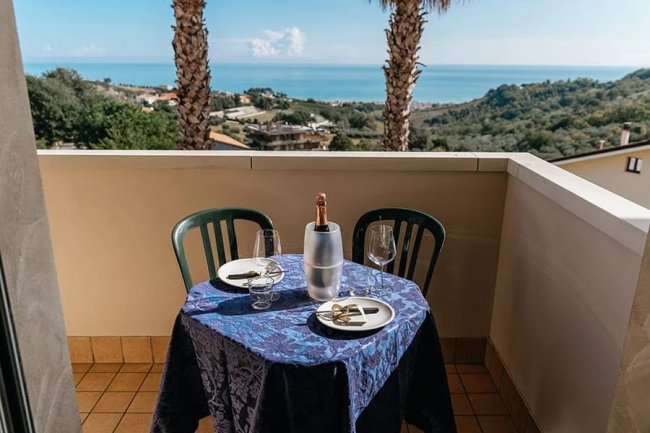 Balcone con tavolo apparecchiato, vista mare.