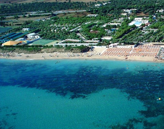 Spiaggia e mare turchese davanti a un villaggio turistico.