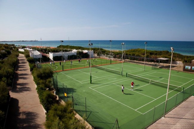 Campi da tennis vicino al mare con persone che giocano.