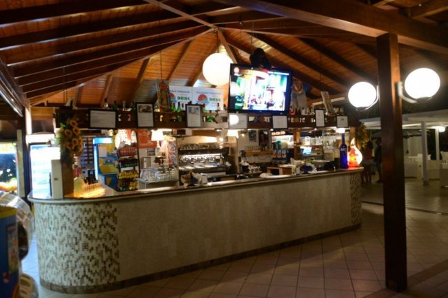 Un bar con tetto in legno e televisore acceso.