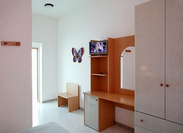 Angolo camera con scrivania, specchio e TV.