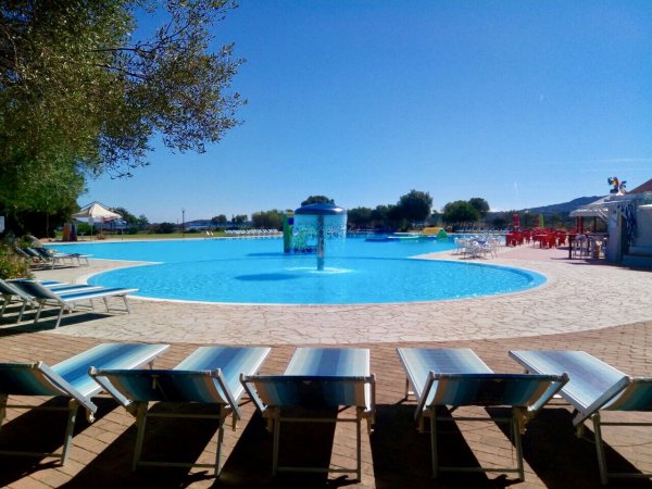Piscina con fontana e lettini intorno.