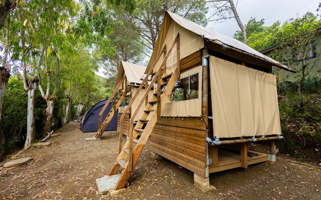 Capanna di legno con scale e tenda.
