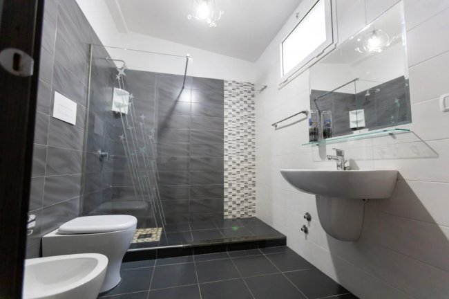 Bagno moderno con doccia e piastrelle scure.