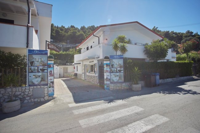 Edificio del residence con piante e cartelli.