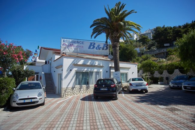 Edificio B&B con parcheggio e auto davanti.