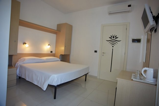 Stanza luminosa con letto matrimoniale e arredi minimalisti.