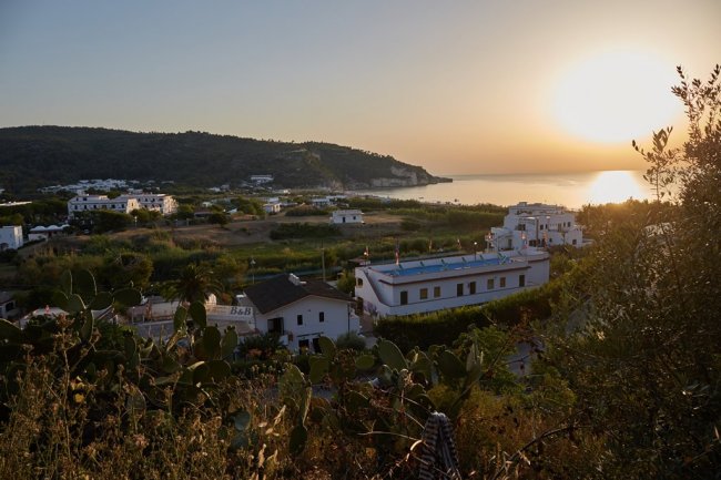 Paesaggio al tramonto con vista mare e edifici.