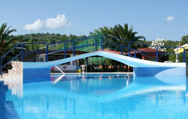 Piscina con ponte e palme sullo sfondo.
