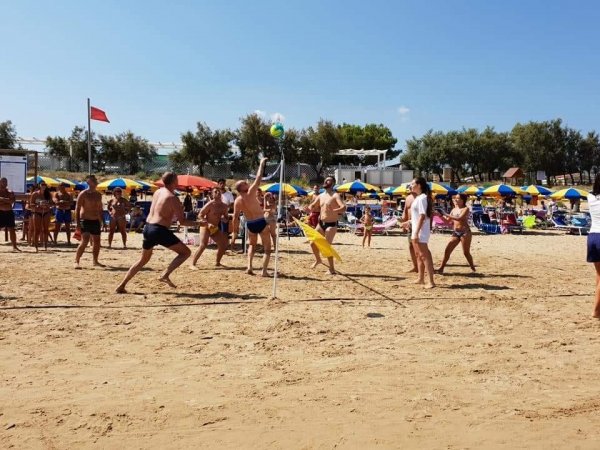Persone giocano a volleyball sulla sabbia.