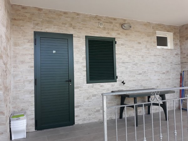 Balcone con porta verde e tavolo.