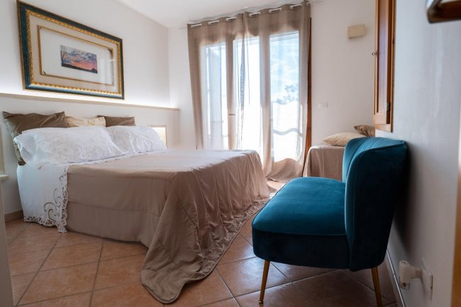 Camera da letto con letto matrimoniale e poltrona blu.