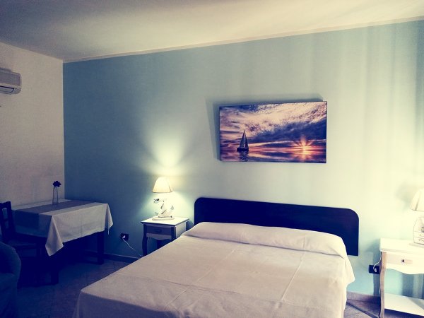 Camera da letto con parete azzurra e dipinto di vela.