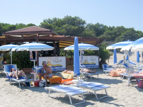 Spiaggia con ombrelloni blu e lettini.
