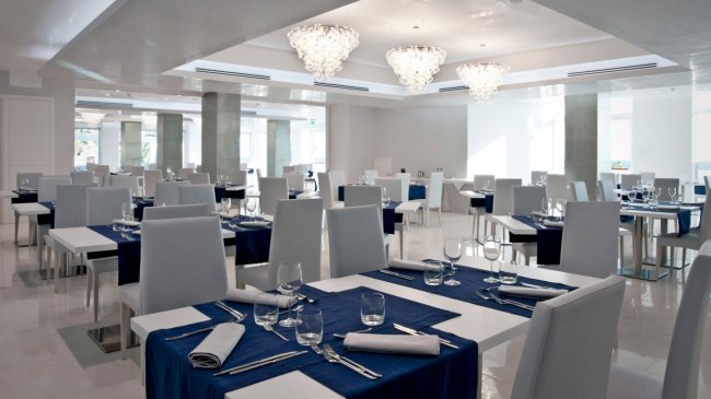 Un elegante ristorante con tavoli apparecchiati con tovagliette blu e sedie bianche.