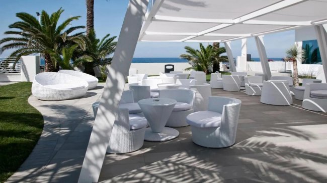 Area lounge all'aperto con sedie e tavolini bianchi moderni.