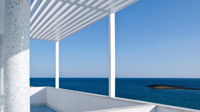 Vista mare con pergola bianca e mare blu all'orizzonte.
